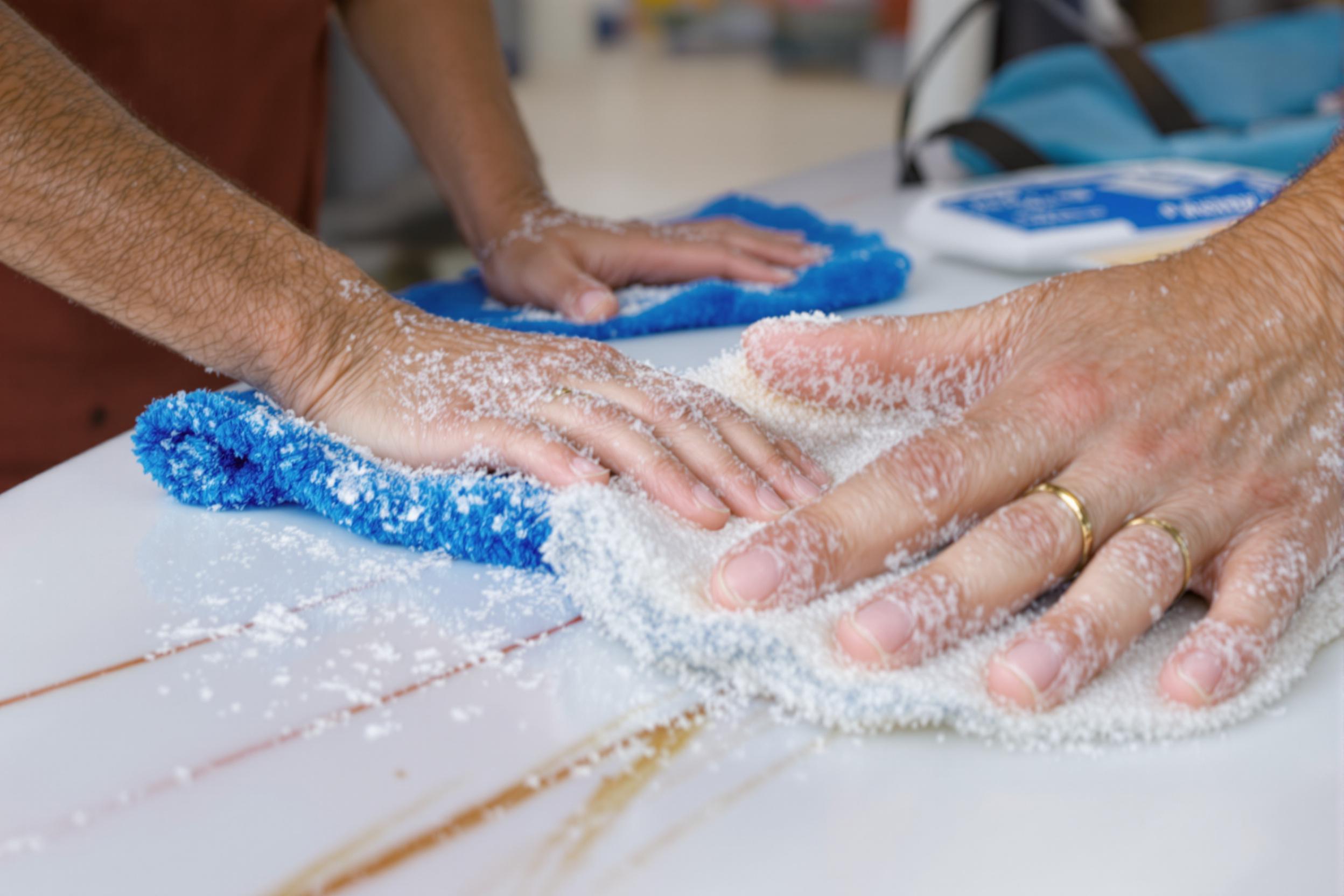 main nettoyant une planche avant la wax
