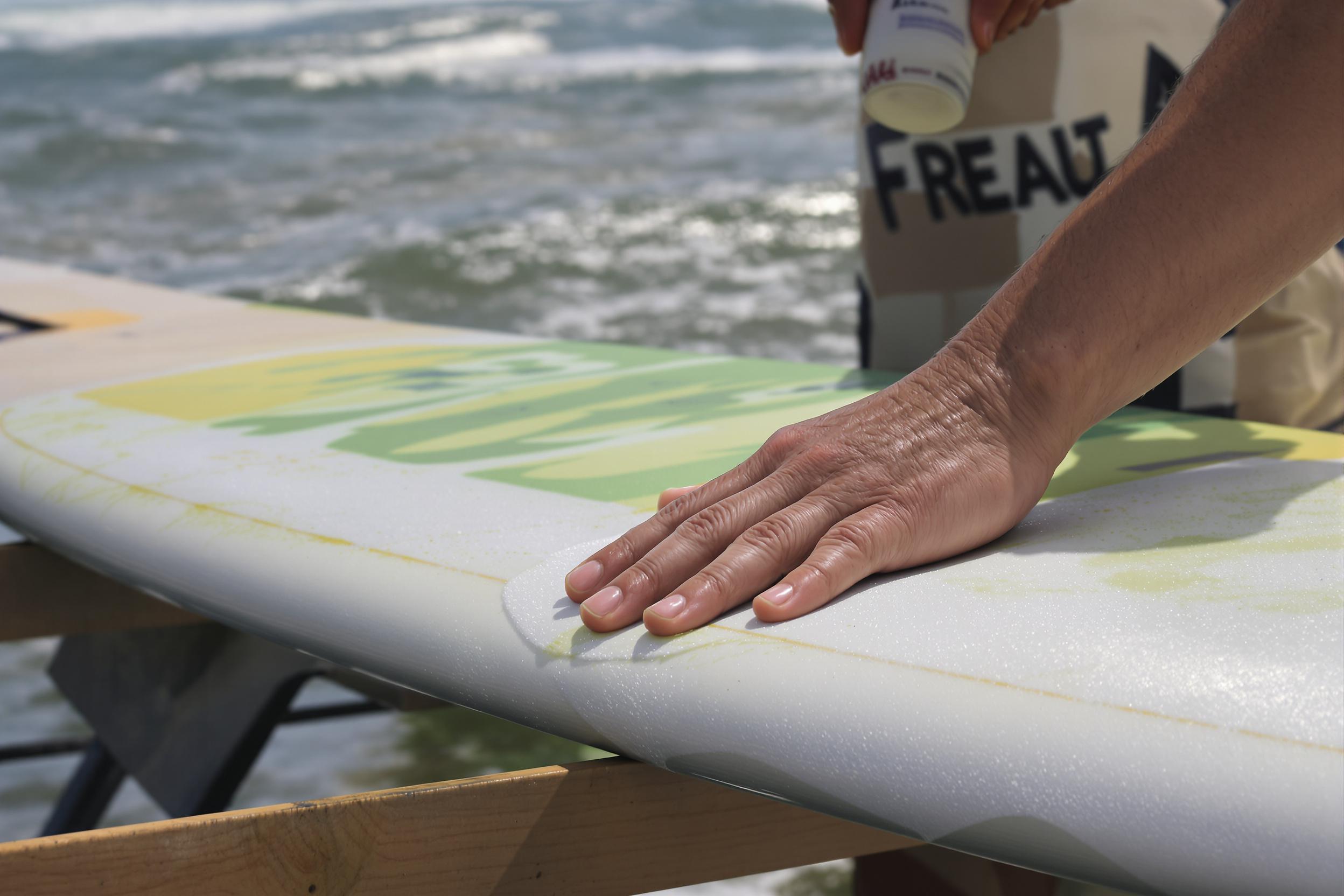 application de wax sur planche de surf